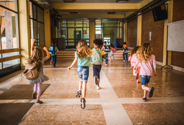 Back view of elementary students running in the school hallway.