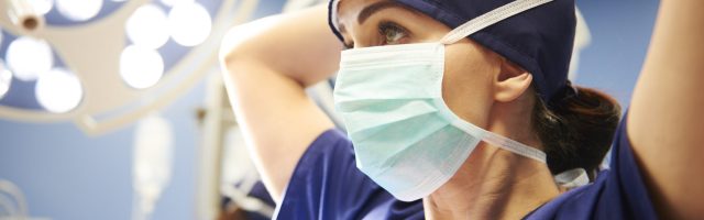 Side view of young female surgeon tying her surgical mask