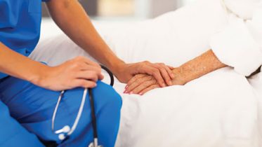 medical doctor holding senior patient's hands and comforting her