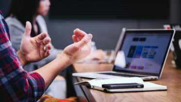 Mesa de trabajo con dos personas y un ordenador portatil